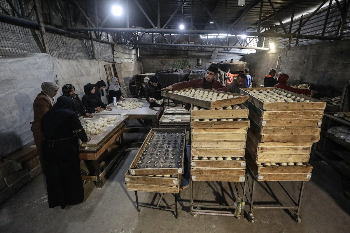 نساء فلسطينيات، زوجات شهداء الحرب، يُجهّزن الخبز لتوزيعه على العائلات النازحة والمحتاجة في مخيم البريج للاجئين وسط قطاع غزة خلال شهر رمضان، في مشهد يُجسّد روح التضامن والصمود في ظلّ الظروف الإنسانية الصعبة، فبراير/شباط 2026. تصوير: معز صالحي