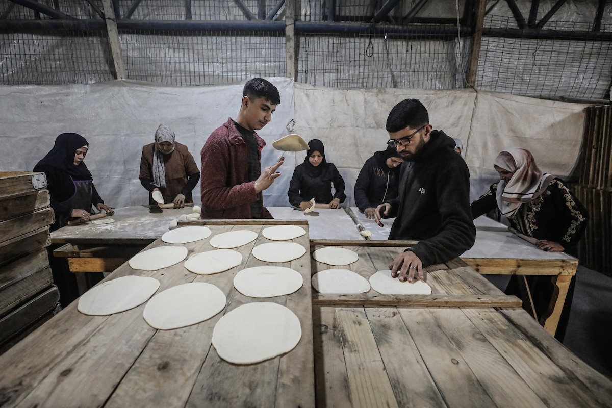 نساء فلسطينيات، زوجات شهداء الحرب، يُجهّزن الخبز لتوزيعه على العائلات النازحة والمحتاجة في مخيم البريج للاجئين وسط قطاع غزة خلال شهر رمضان، في مشهد يُجسّد روح التضامن والصمود في ظلّ الظروف الإنسانية الصعبة، فبراير/شباط 2026. تصوير: معز صالحي