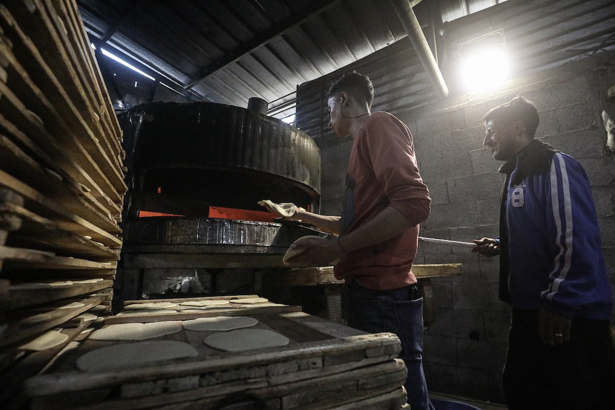 نساء فلسطينيات، زوجات شهداء الحرب، يُجهّزن الخبز لتوزيعه على العائلات النازحة والمحتاجة في مخيم البريج للاجئين وسط قطاع غزة خلال شهر رمضان، في مشهد يُجسّد روح التضامن والصمود في ظلّ الظروف الإنسانية الصعبة، فبراير/شباط 2026. تصوير: معز صالحي