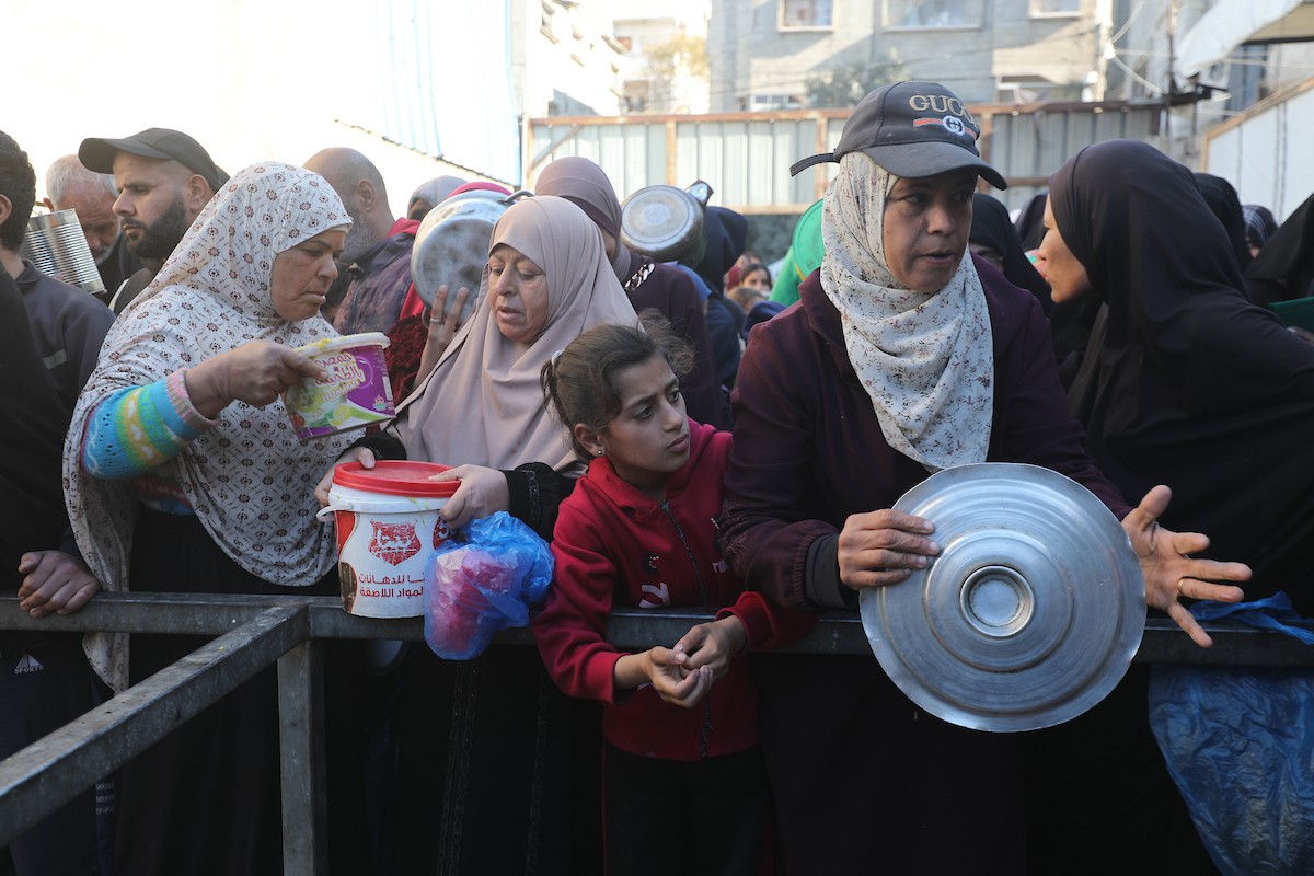 يتجمع فلسطينيون لتناول وجبة ساخنة وزعتها إحدى الجمعيات الخيرية، وسط أزمة غذائية مستمرة بسبب محدودية المساعدات الإنسانية خلال شهر رمضان في مخيم النصيرات للاجئين وسط قطاع غزة. ٢٣ فبرايرشباط ٢٠٢٦. تصوير معز صالحي