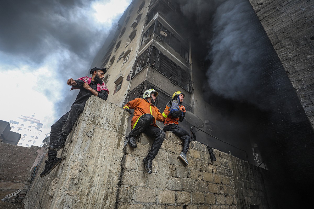 طواقم الدفاع المدني ومتطوعون من المواطنين أثناء محاولة إخماد حريق اندلع في مستودع تابع لمنظمة إغاثة في حي الرمال، غرب مدينة غزة، في 13 فبراير/شباط 2026. صورة: عمر أشتوي