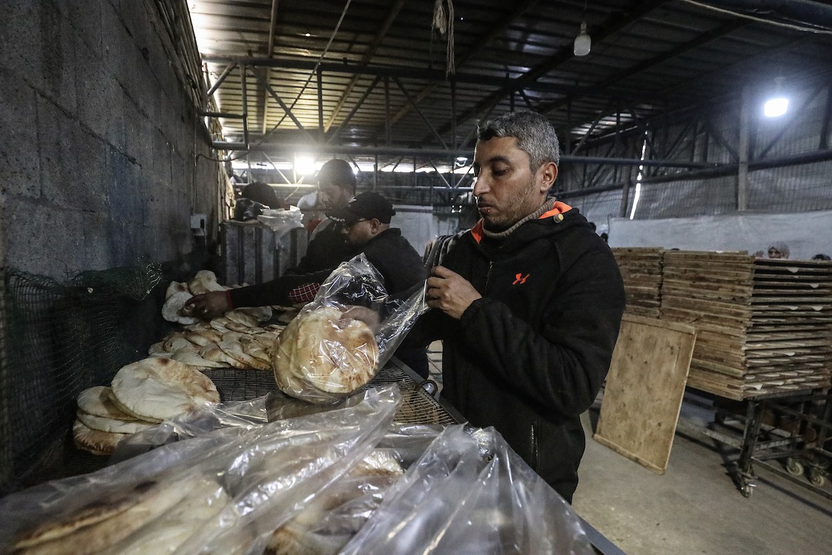 نساء فلسطينيات، زوجات شهداء الحرب، يُجهّزن الخبز لتوزيعه على العائلات النازحة والمحتاجة في مخيم البريج للاجئين وسط قطاع غزة خلال شهر رمضان، في مشهد يُجسّد روح التضامن والصمود في ظلّ الظروف الإنسانية الصعبة، فبراير/شباط 2026. تصوير: معز صالحي