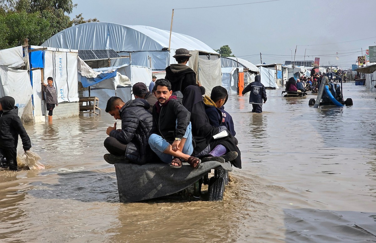 يحاول الفلسطينيون التنقل بعد أن غمرت مياه الأمطار الشوارع وخيام النازحين في خان يونس، جنوب قطاع غزة، في 24 فبراير/شباط 2026. وقد دُمرت البنية التحتية في قطاع غزة على نطاق واسع جراء الحرب والهجمات الإسرائيلية. (صورة: طارق محمد)