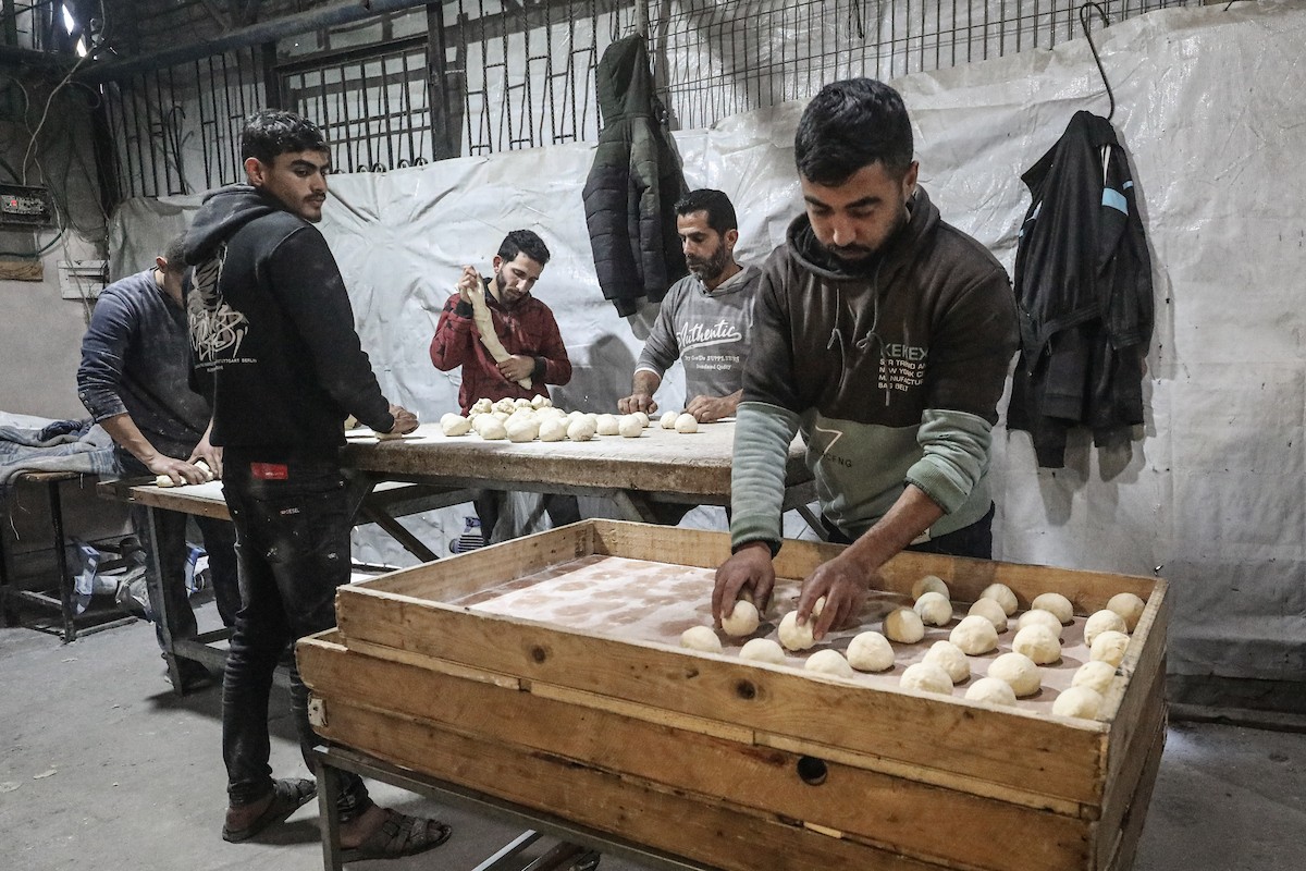 نساء فلسطينيات، زوجات شهداء الحرب، يُجهّزن الخبز لتوزيعه على العائلات النازحة والمحتاجة في مخيم البريج للاجئين وسط قطاع غزة خلال شهر رمضان، في مشهد يُجسّد روح التضامن والصمود في ظلّ الظروف الإنسانية الصعبة، فبراير/شباط 2026. تصوير: معز صالحي
