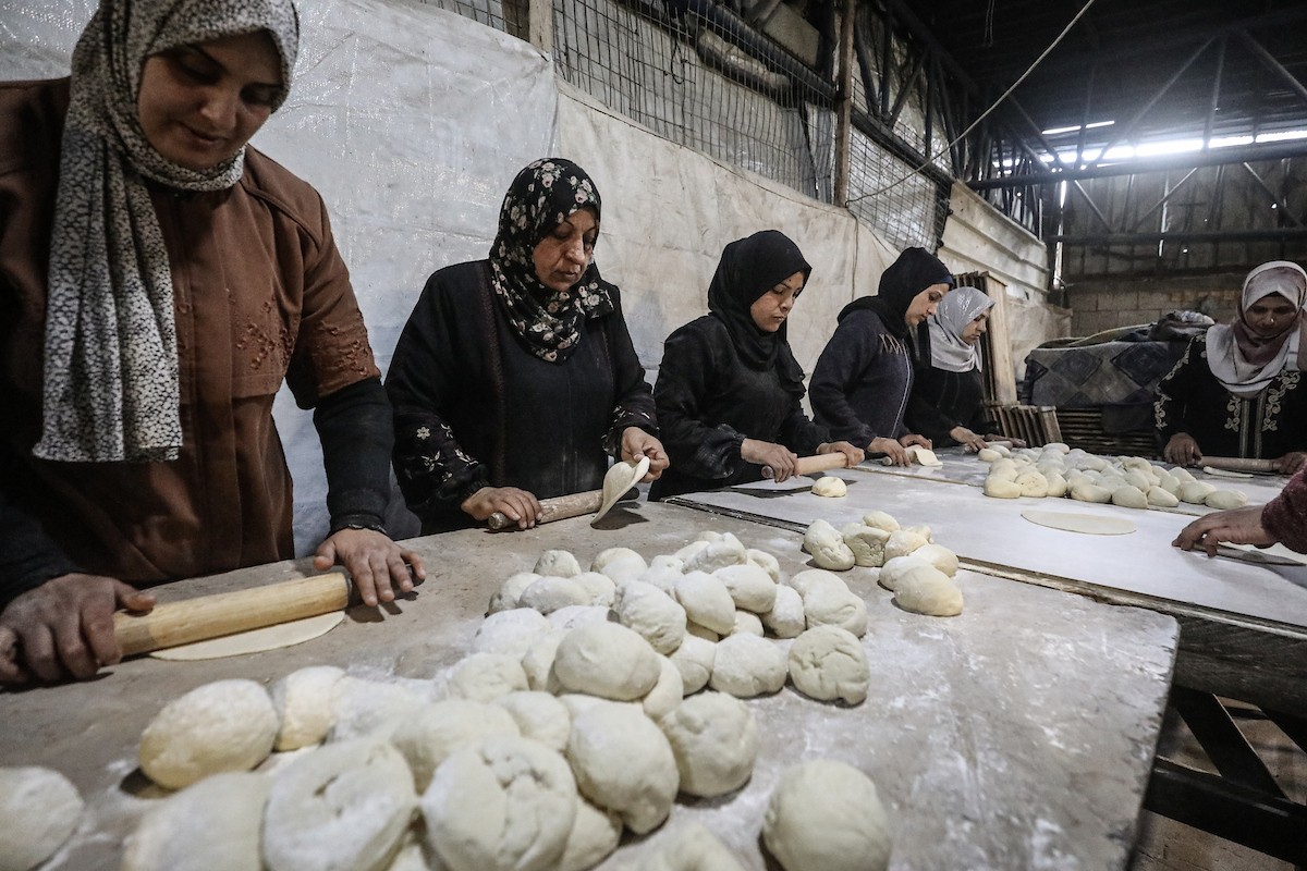 نساء فلسطينيات، زوجات شهداء الحرب، يُجهّزن الخبز لتوزيعه على العائلات النازحة والمحتاجة في مخيم البريج للاجئين وسط قطاع غزة خلال شهر رمضان، في مشهد يُجسّد روح التضامن والصمود في ظلّ الظروف الإنسانية الصعبة، فبراير/شباط 2026. تصوير: معز صالحي