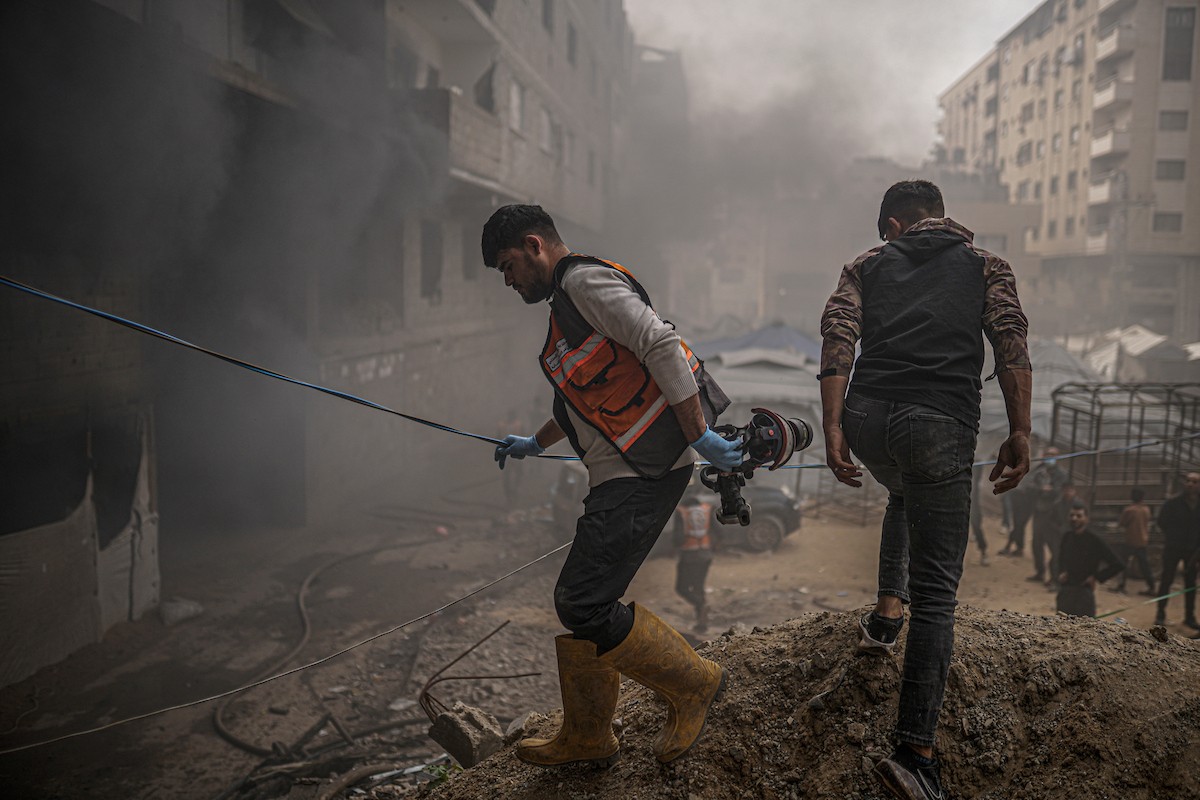 طواقم الدفاع المدني ومتطوعون من المواطنين أثناء محاولة إخماد حريق اندلع في مستودع تابع لمنظمة إغاثة في حي الرمال، غرب مدينة غزة، في 13 فبراير/شباط 2026. صورة: عمر أشتوي