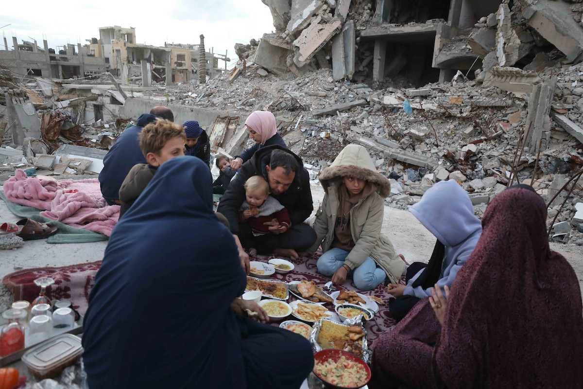 عائلة فلسطينية تتناول إفطارها خلال شهر رمضان على سطح منزلها الذي دمره قصف جوي إسرائيلي خلال حرب غزة في 27 فبراير/شباط 2026. صورة: عمر أشتوي
