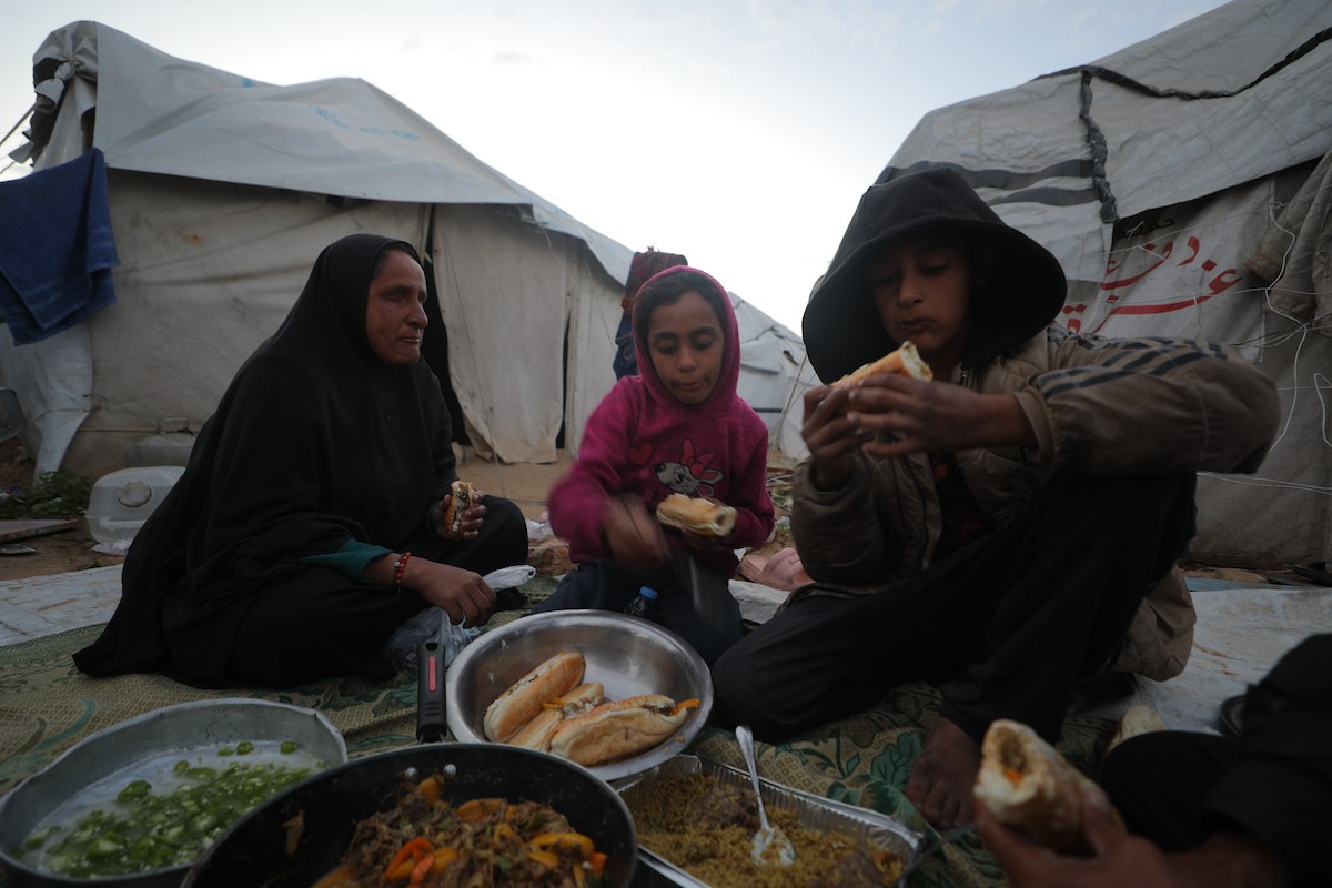 عائلة فلسطينية كفيفة تتناول وجبة الإفطار خارج خيمتها في مخيم بوسط قطاع غزة خلال شهر رمضان