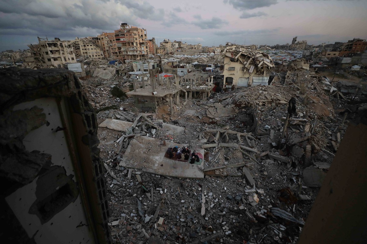 عائلة فلسطينية تتناول إفطارها خلال شهر رمضان على سطح منزلها الذي دمره قصف جوي إسرائيلي خلال حرب غزة في 27 فبراير/شباط 2026. صورة: عمر أشتوي