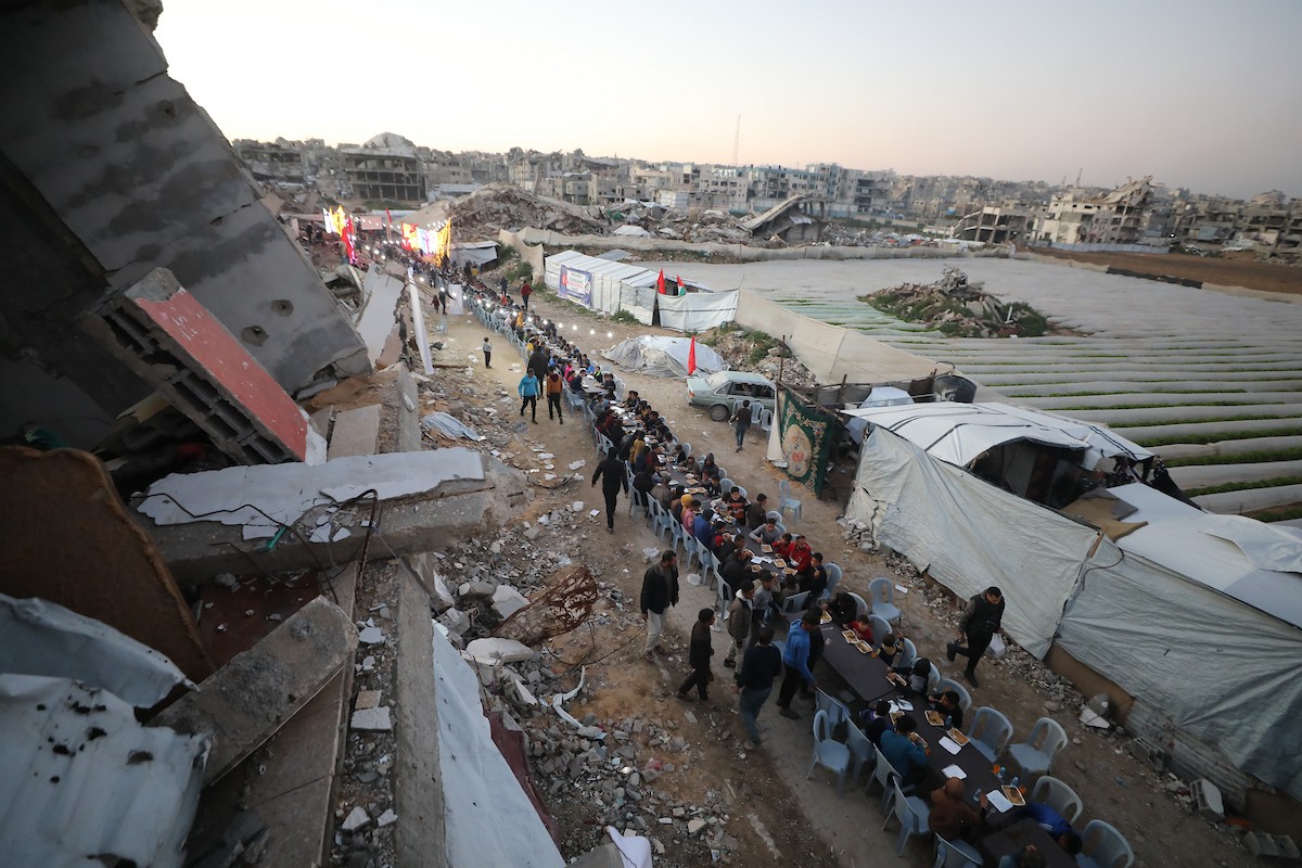يتجمع فلسطينيون نازحون لتناول وجبة الإفطار وسط أنقاض المباني المدمرة في مدينة غزة، خلال شهر رمضان المبارك، في 25 فبراير/شباط 2026. صورة: عمر أشتوي