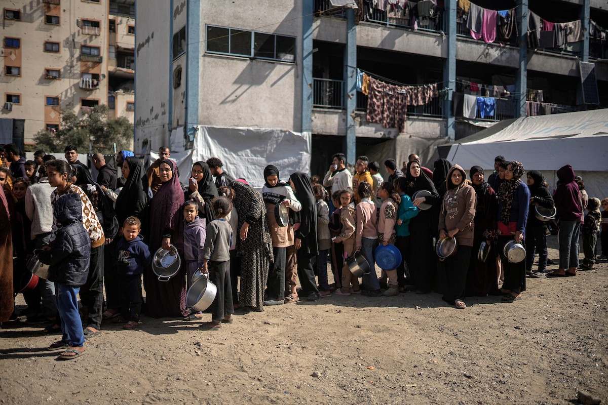 فلسطينيون بينهم أطفال ونساء يتلقون مساعدات غذائية وزعتها منظمات خيرية في أحد مراكز الإيواء بمدينة غزة، وسط أزمة غذائية مستمرة ناجمة عن محدودية المساعدات الإنسانية والظروف الإنسانية المتردية التي يواجهها النازحون، ١٢ فبراير/شباط ٢٠٢٦. تصوير: عمر أشتوي