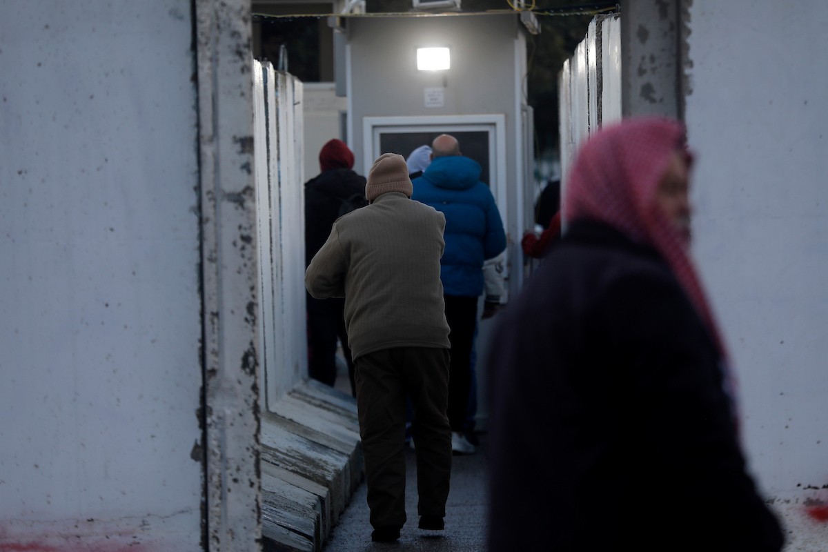 فلسطينيون يعبرون نقطة تفتيش إسرائيلية، وهي نقطة عبور ضرورية لمغادرة مدينة بيت لحم في الضفة الغربية والوصول إلى المسجد الأقصى في القدس لأداء صلاة الجمعة الثانية من شهر رمضان، ٢٧ فبراير/شباط ٢٠٢٦. تصوير: مأمون وزواز