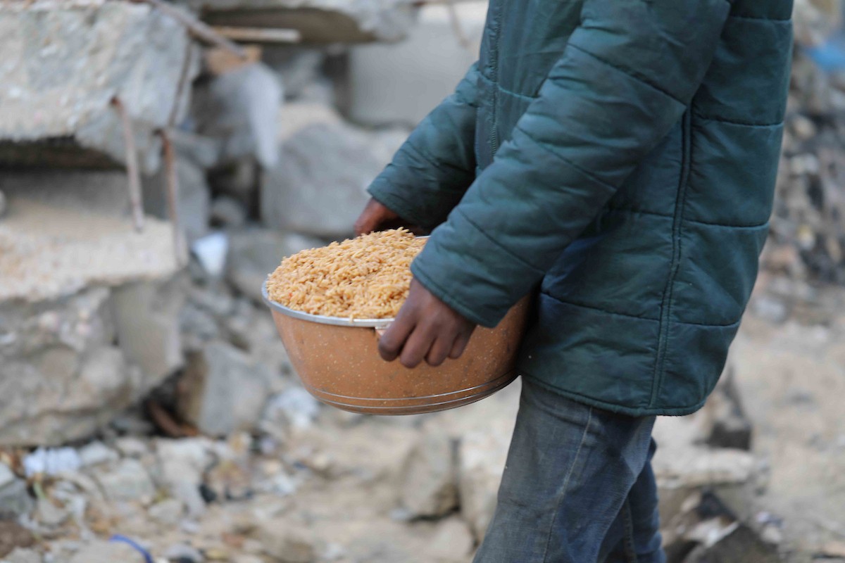 تجمع فلسطينيون نازحون، بينهم أطفال ونساء، حاملين أوعية طعام لتلقي وجبات ساخنة وزعتها جمعيات خيرية قبل الإفطار في مدينة غزة في 27 فبراير/شباط 2026.صورة: عمر أشتوي