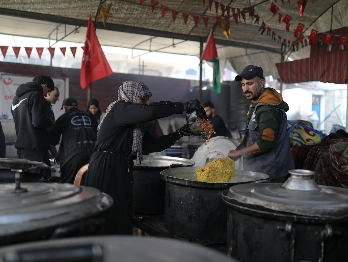 يتجمع فلسطينيون نازحون لتناول وجبة إفطارهم الرمضانية في مطبخ خيري بمخيم النصيرات للاجئين وسط قطاع غزة، في 24 فبراير/شباط 2026. ويواجه النازحون ظروفًا معيشية قاسية نتيجة انعدام الدخل ونقص المساعدات الإنسانية. (صورة: رمزي أبو عامر / apaimages)