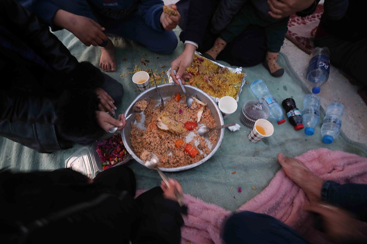 عائلة فلسطينية تتناول إفطارها خلال شهر رمضان على سطح منزلها الذي دمره قصف جوي إسرائيلي خلال حرب غزة في 27 فبراير/شباط 2026. صورة: عمر أشتوي