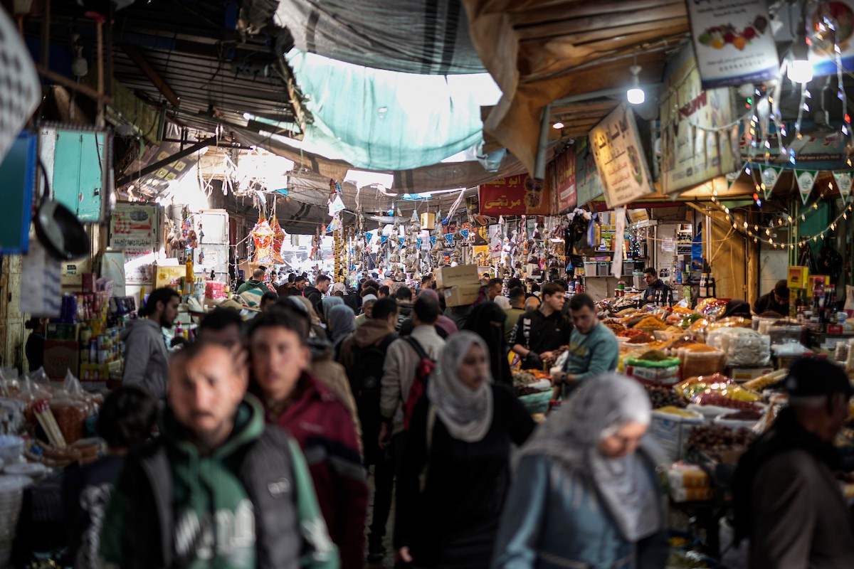 يتسوق الفلسطينيون في أول ليلة من شهر رمضان المبارك في سوق الزاوية، الواقع في قلب مدينة غزة والذي تضرر بشدة جراء الحرب الإسرائيلية. يعرض الباعة بضائعهم على أكشاك مزينة بالفوانيس والأضواء وأطعمة رمضان. مدينة غزة، 17 فبراير/شباط 2026. تصوير: عمر أشتوي