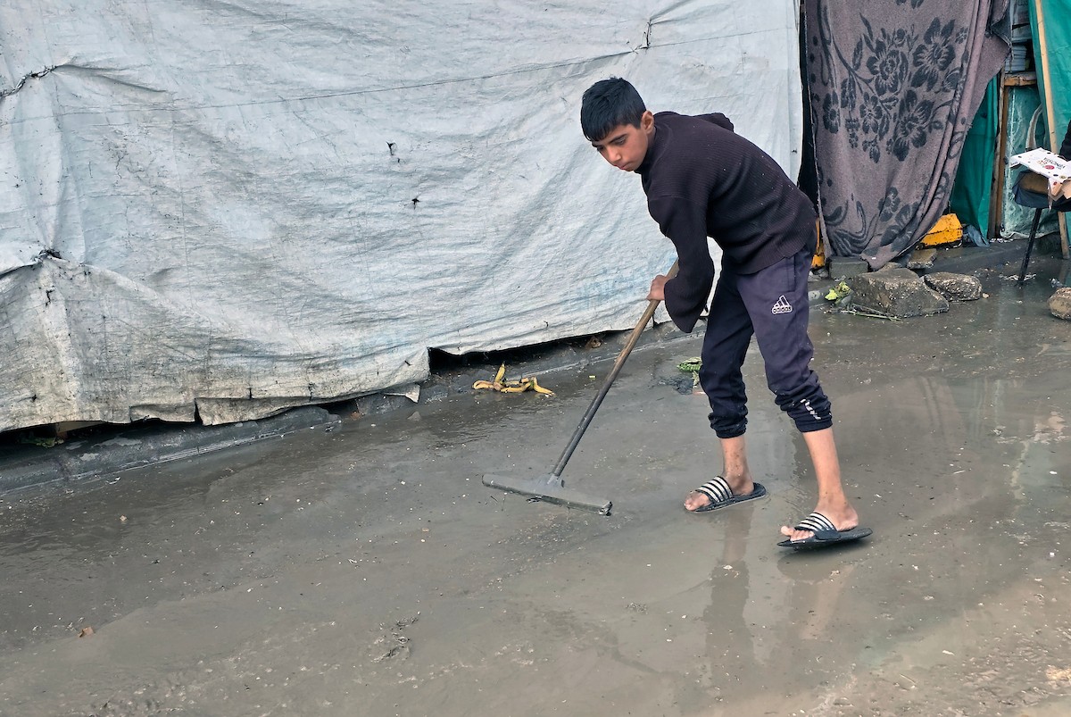 يحاول الفلسطينيون التنقل بعد أن غمرت مياه الأمطار الشوارع وخيام النازحين في خان يونس، جنوب قطاع غزة، في 24 فبراير/شباط 2026. وقد دُمرت البنية التحتية في قطاع غزة على نطاق واسع جراء الحرب والهجمات الإسرائيلية. (صورة: طارق محمد)