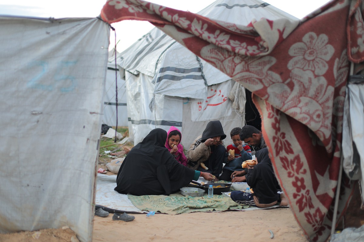 عائلة فلسطينية كفيفة تتناول وجبة الإفطار خارج خيمتها في مخيم بوسط قطاع غزة خلال شهر رمضان