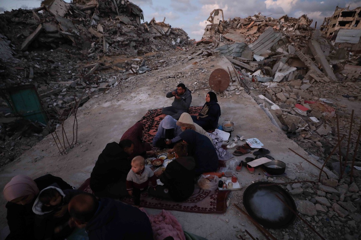 عائلة فلسطينية تتناول إفطارها خلال شهر رمضان على سطح منزلها الذي دمره قصف جوي إسرائيلي خلال حرب غزة في 27 فبراير/شباط 2026. صورة: عمر أشتوي