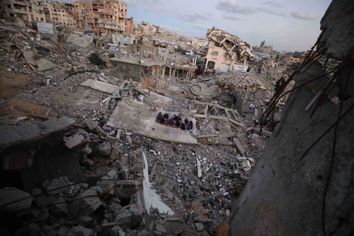 عائلة فلسطينية تتناول إفطارها خلال شهر رمضان على سطح منزلها الذي دمره قصف جوي إسرائيلي خلال حرب غزة في 27 فبراير/شباط 2026. صورة: عمر أشتوي