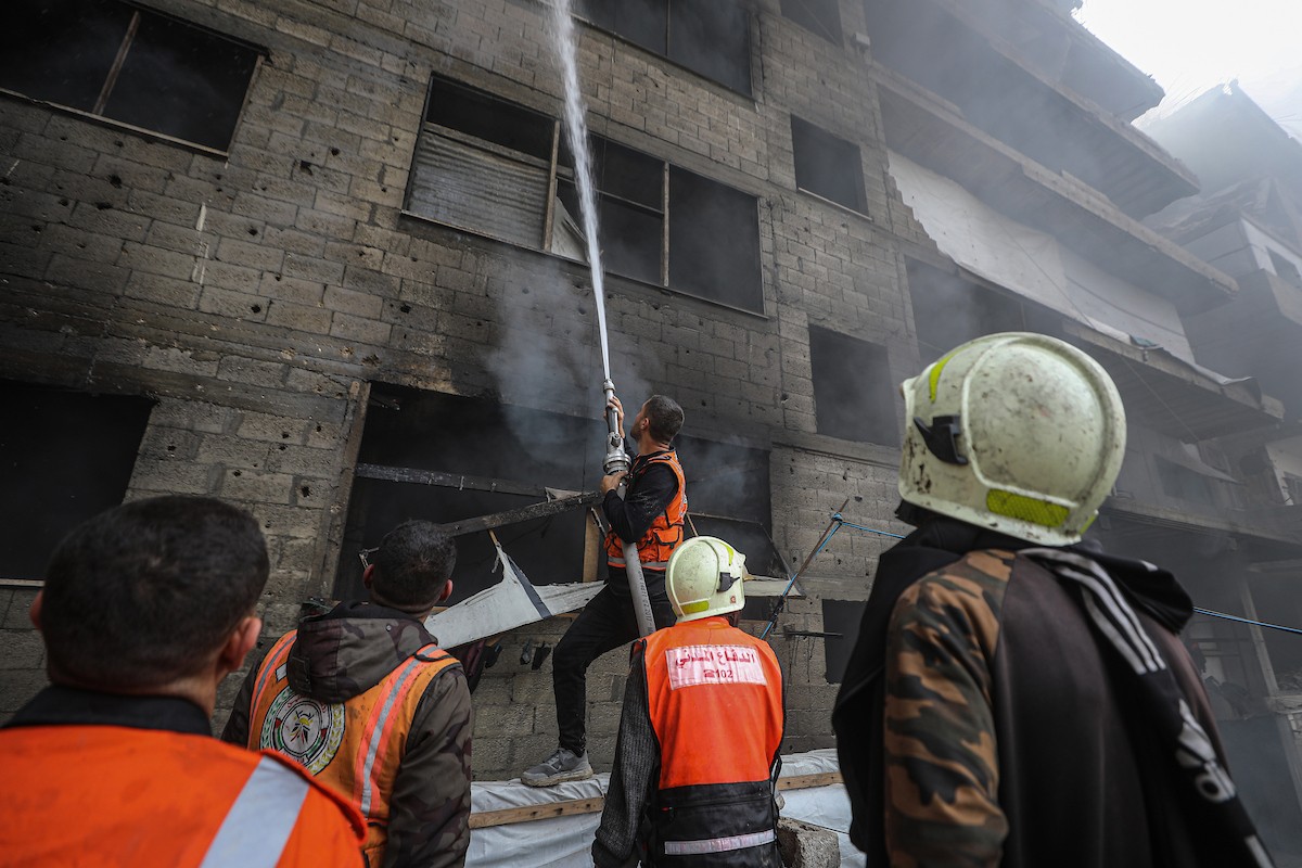 طواقم الدفاع المدني ومتطوعون من المواطنين أثناء محاولة إخماد حريق اندلع في مستودع تابع لمنظمة إغاثة في حي الرمال، غرب مدينة غزة، في 13 فبراير/شباط 2026. صورة: عمر أشتوي