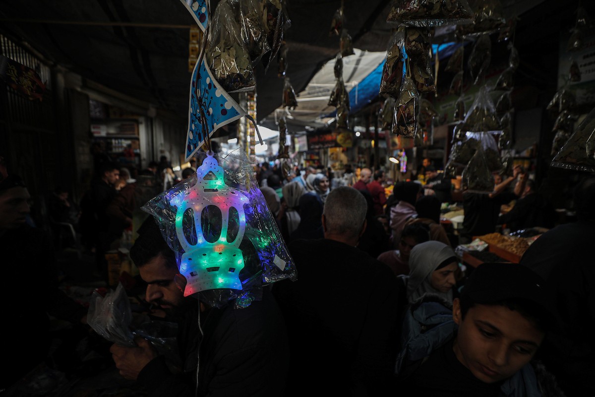يتسوق الفلسطينيون في أول ليلة من شهر رمضان المبارك في سوق الزاوية، الواقع في قلب مدينة غزة والذي تضرر بشدة جراء الحرب الإسرائيلية. يعرض الباعة بضائعهم على أكشاك مزينة بالفوانيس والأضواء وأطعمة رمضان. مدينة غزة، 17 فبراير/شباط 2026. تصوير: عمر أشتوي