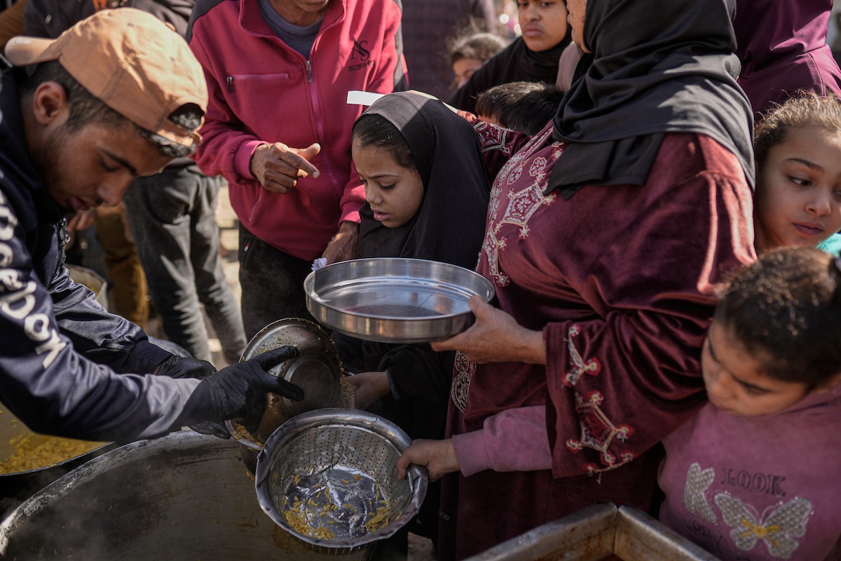 فلسطينيون بينهم أطفال ونساء يتلقون مساعدات غذائية وزعتها منظمات خيرية في أحد مراكز الإيواء بمدينة غزة، وسط أزمة غذائية مستمرة ناجمة عن محدودية المساعدات الإنسانية والظروف الإنسانية المتردية التي يواجهها النازحون، ١٢ فبراير/شباط ٢٠٢٦. تصوير: عمر أشتوي