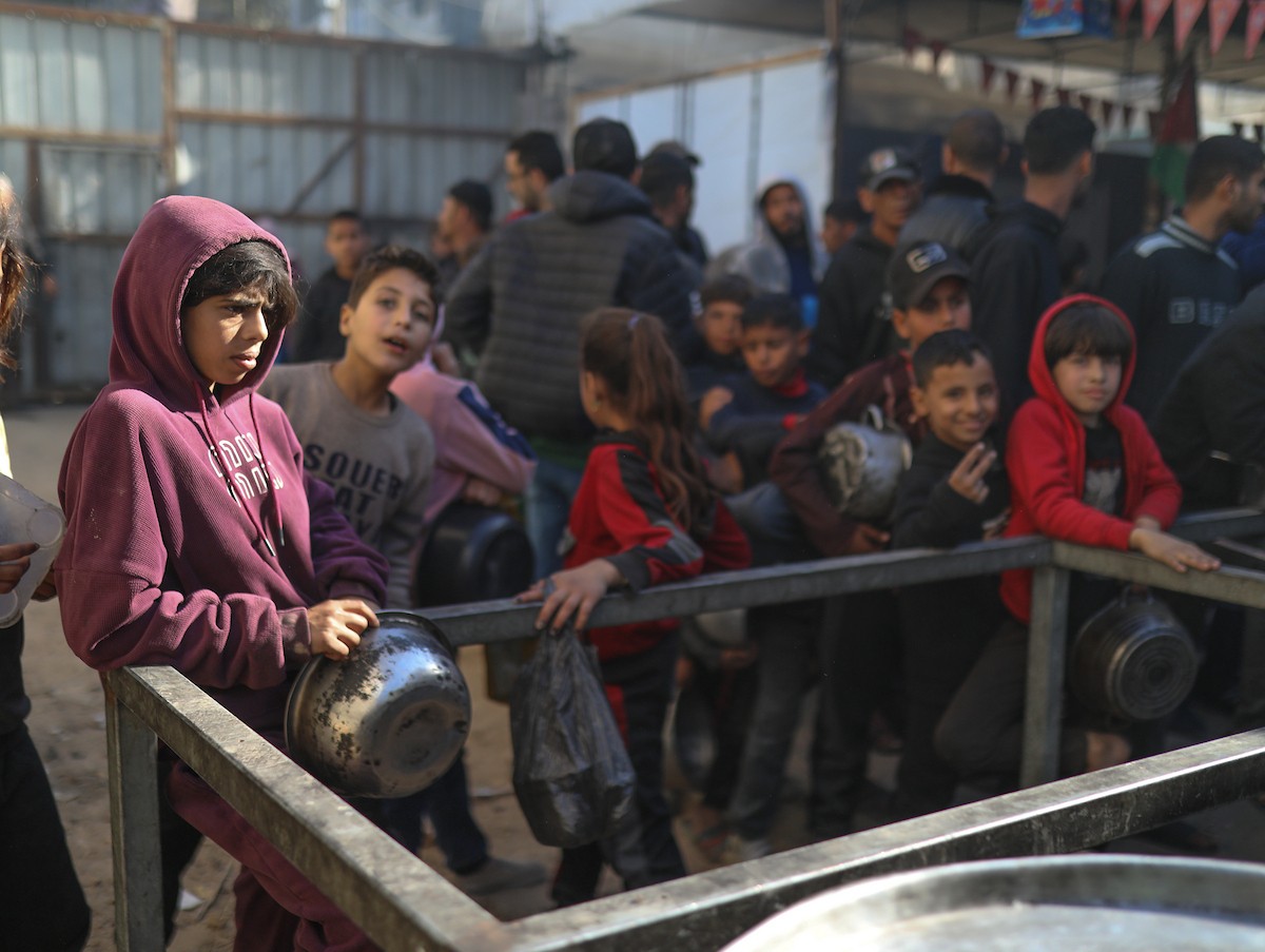 يتجمع فلسطينيون نازحون لتناول وجبة إفطارهم الرمضانية في مطبخ خيري بمخيم النصيرات للاجئين وسط قطاع غزة، في 24 فبراير/شباط 2026. ويواجه النازحون ظروفًا معيشية قاسية نتيجة انعدام الدخل ونقص المساعدات الإنسانية. (صورة: رمزي أبو عامر / apaimages)