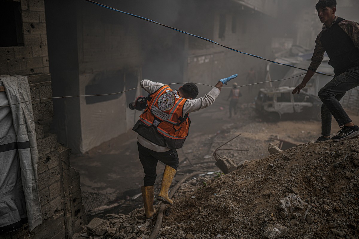 طواقم الدفاع المدني ومتطوعون من المواطنين أثناء محاولة إخماد حريق اندلع في مستودع تابع لمنظمة إغاثة في حي الرمال، غرب مدينة غزة، في 13 فبراير/شباط 2026. صورة: عمر أشتوي