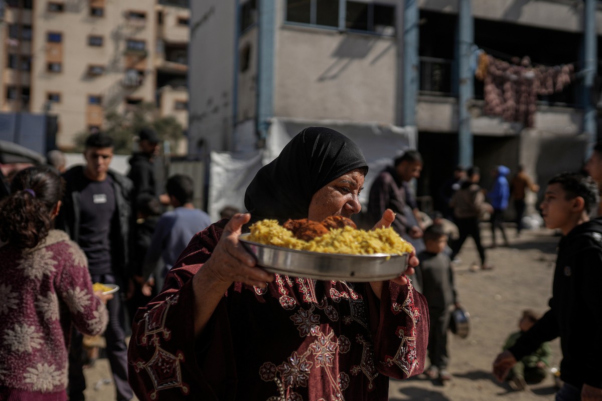 فلسطينيون بينهم أطفال ونساء يتلقون مساعدات غذائية وزعتها منظمات خيرية في أحد مراكز الإيواء بمدينة غزة، وسط أزمة غذائية مستمرة ناجمة عن محدودية المساعدات الإنسانية والظروف الإنسانية المتردية التي يواجهها النازحون، ١٢ فبراير/شباط ٢٠٢٦. تصوير: عمر أشتوي