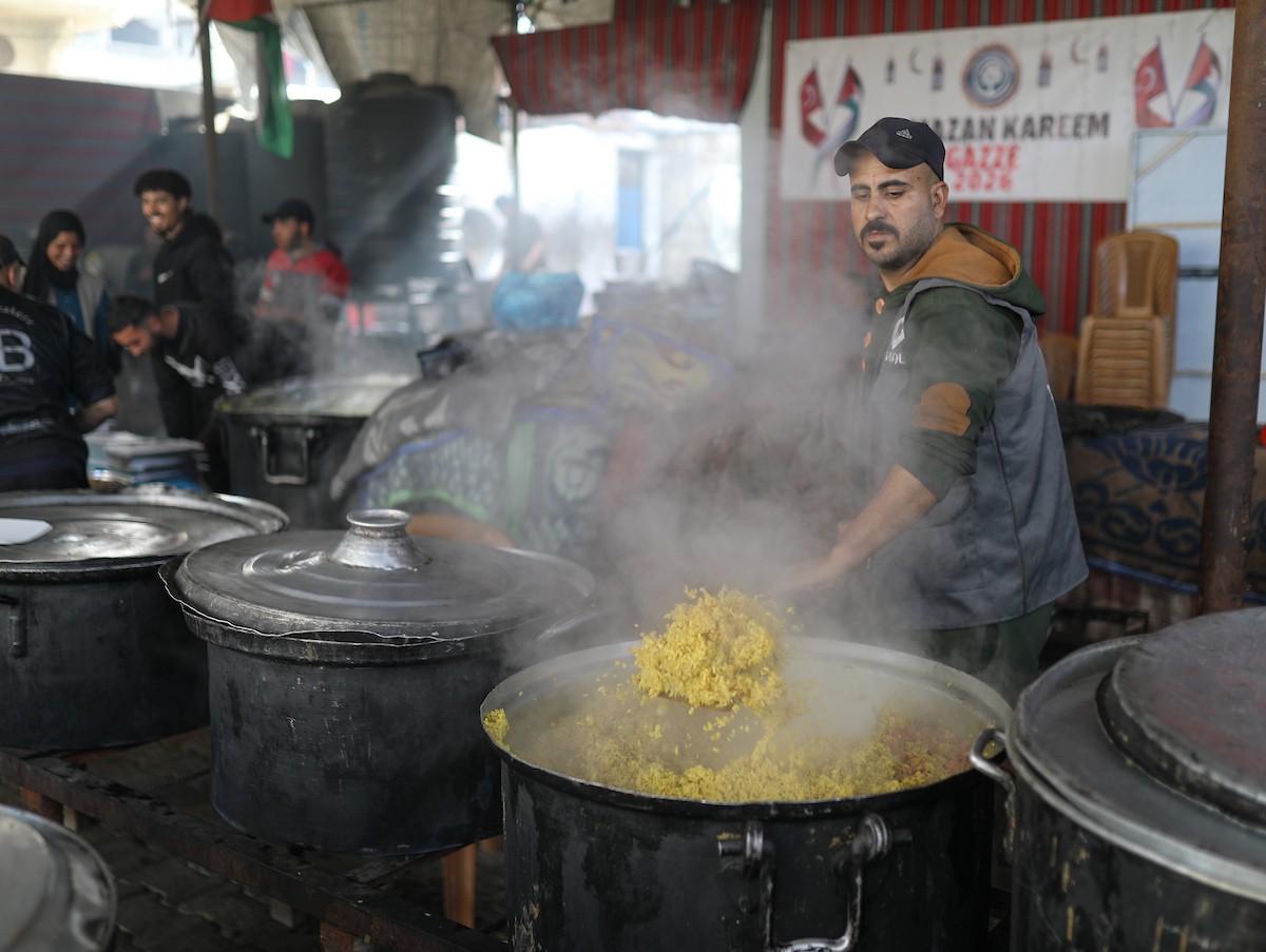 يتجمع فلسطينيون نازحون لتناول وجبة إفطارهم الرمضانية في مطبخ خيري بمخيم النصيرات للاجئين وسط قطاع غزة، في 24 فبراير/شباط 2026. ويواجه النازحون ظروفًا معيشية قاسية نتيجة انعدام الدخل ونقص المساعدات الإنسانية. (صورة: رمزي أبو عامر / apaimages)