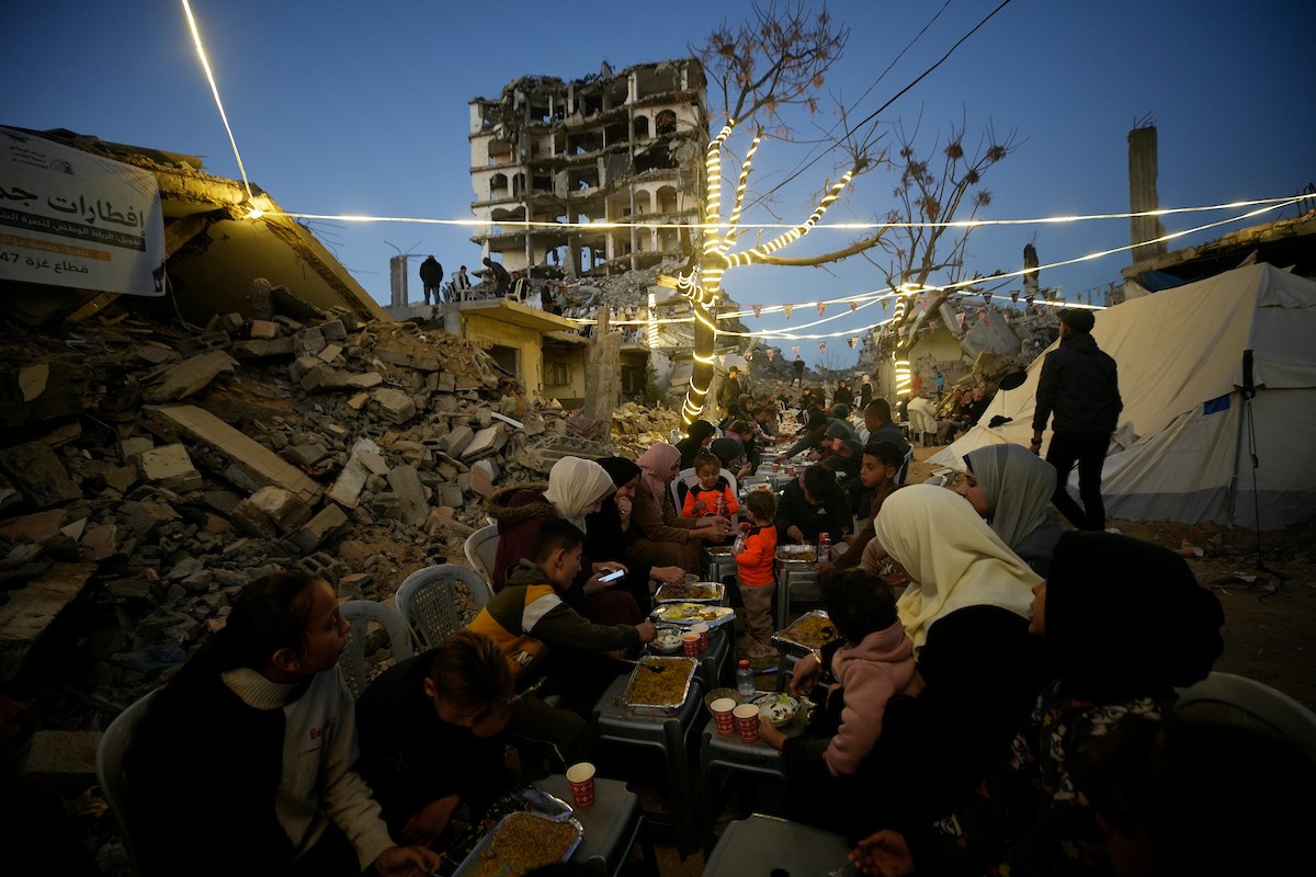 يتجمع الفلسطينيون بين المنازل المدمرة لتناول وجبة الإفطار معًا خلال شهر رمضان المبارك في شمال قطاع غزة، 22 فبراير/شباط 2026. صورة: عمر أشتوي