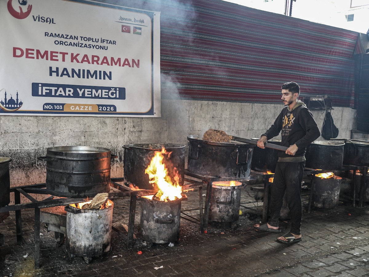 يتجمع فلسطينيون نازحون لتناول وجبة إفطارهم الرمضانية في مطبخ خيري بمخيم النصيرات للاجئين وسط قطاع غزة، في 24 فبراير/شباط 2026. ويواجه النازحون ظروفًا معيشية قاسية نتيجة انعدام الدخل ونقص المساعدات الإنسانية. (صورة: رمزي أبو عامر / apaimages)