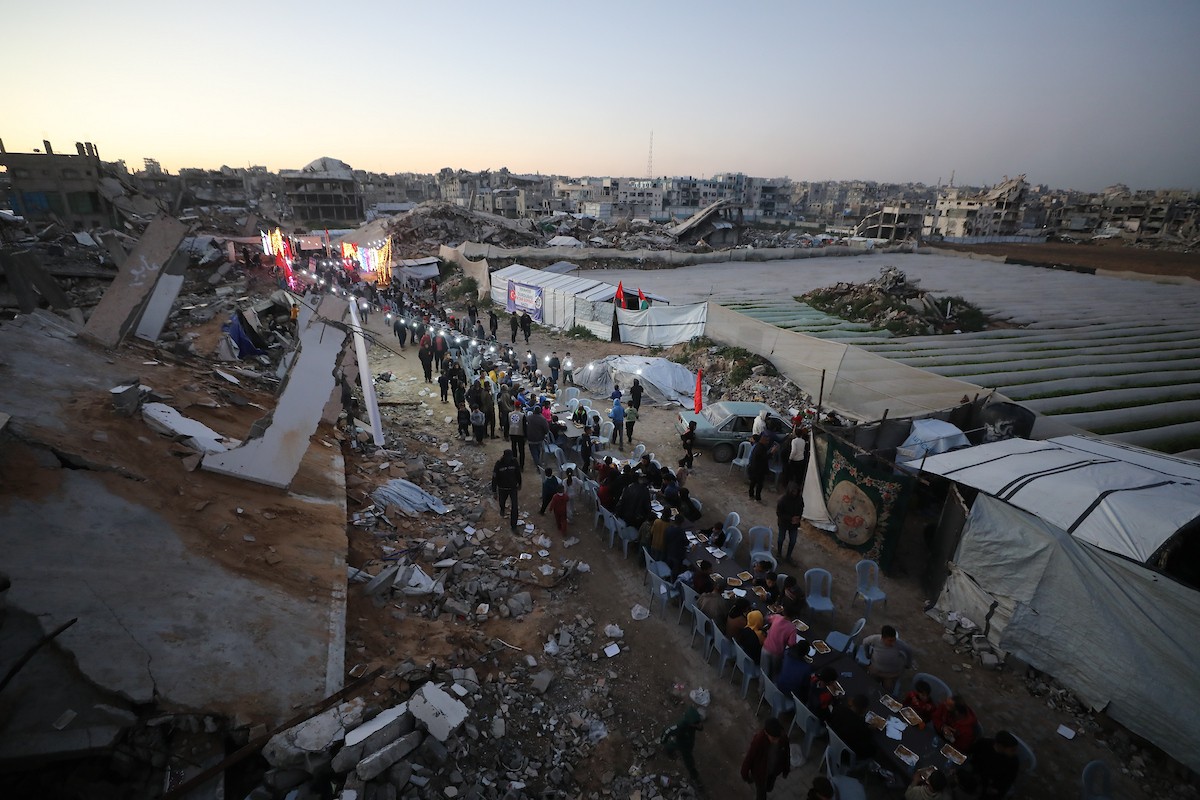 يتجمع فلسطينيون نازحون لتناول وجبة الإفطار وسط أنقاض المباني المدمرة في مدينة غزة، خلال شهر رمضان المبارك، في 25 فبراير/شباط 2026. صورة: عمر أشتوي