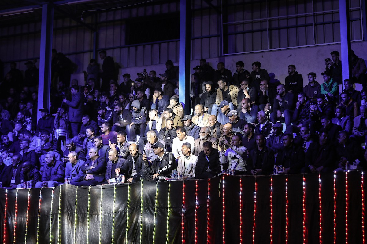 لاعبون فلسطينيون من فريقي النصيرات ورفح يتنافسون خلال مباراة كرة قدم على ملعب نادي خدمات النصيرات، ضمن بطولة غزة الرمضانية، بحضور حشد جماهيري كبير، في مخيم النصيرات بوسط قطاع غزة، بتاريخ 21 فبراير/شباط 2026. تصوير: معز صالحي / apaimages