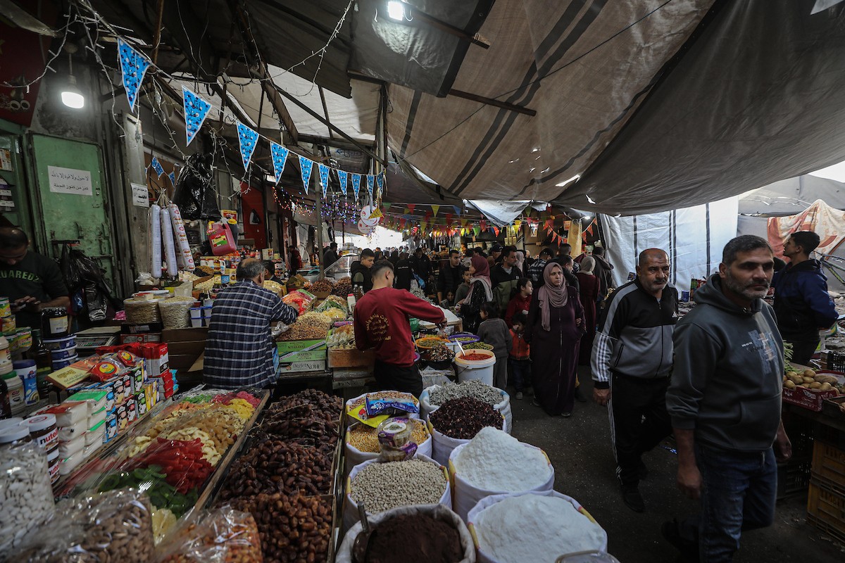 يتسوق الفلسطينيون في أول ليلة من شهر رمضان المبارك في سوق الزاوية، الواقع في قلب مدينة غزة والذي تضرر بشدة جراء الحرب الإسرائيلية. يعرض الباعة بضائعهم على أكشاك مزينة بالفوانيس والأضواء وأطعمة رمضان. مدينة غزة، 17 فبراير/شباط 2026. تصوير: عمر أشتوي