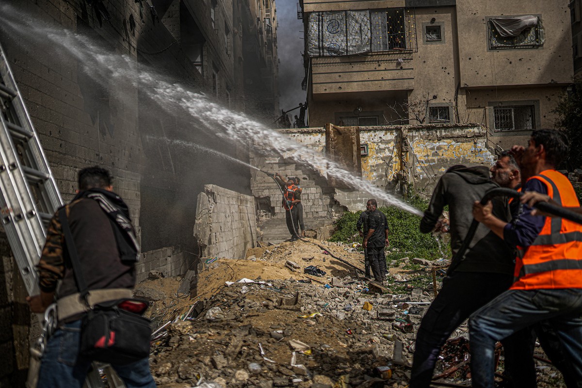 طواقم الدفاع المدني ومتطوعون من المواطنين أثناء محاولة إخماد حريق اندلع في مستودع تابع لمنظمة إغاثة في حي الرمال، غرب مدينة غزة، في 13 فبراير/شباط 2026. صورة: عمر أشتوي