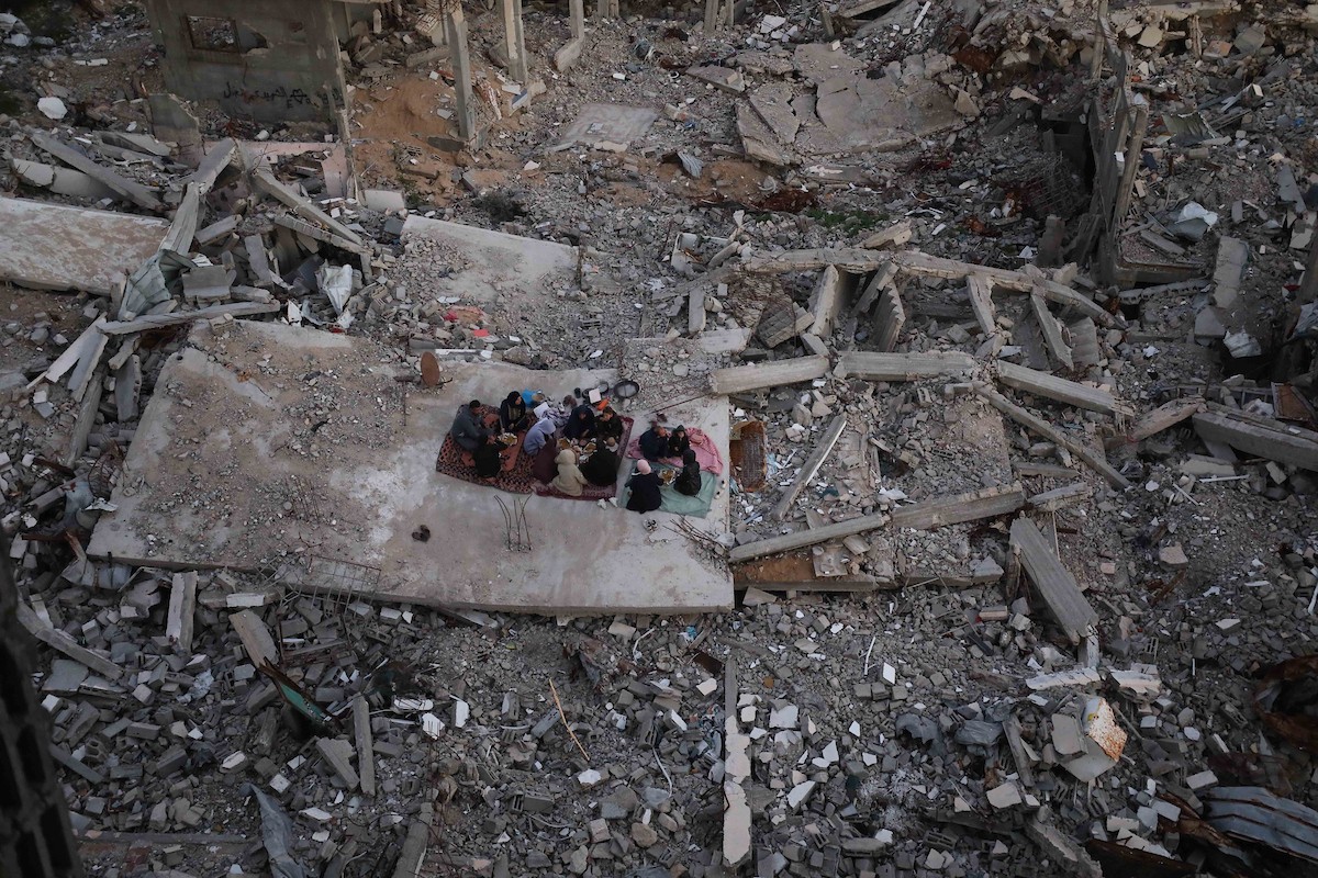 عائلة فلسطينية تتناول إفطارها خلال شهر رمضان على سطح منزلها الذي دمره قصف جوي إسرائيلي خلال حرب غزة في 27 فبراير/شباط 2026. صورة: عمر أشتوي