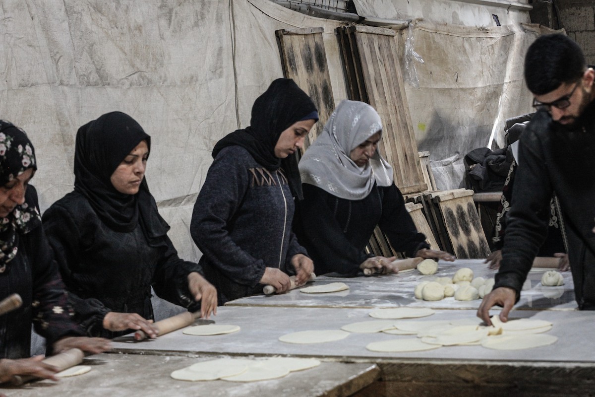 نساء فلسطينيات، زوجات شهداء الحرب، يُجهّزن الخبز لتوزيعه على العائلات النازحة والمحتاجة في مخيم البريج للاجئين وسط قطاع غزة خلال شهر رمضان، في مشهد يُجسّد روح التضامن والصمود في ظلّ الظروف الإنسانية الصعبة، فبراير/شباط 2026. تصوير: معز صالحي