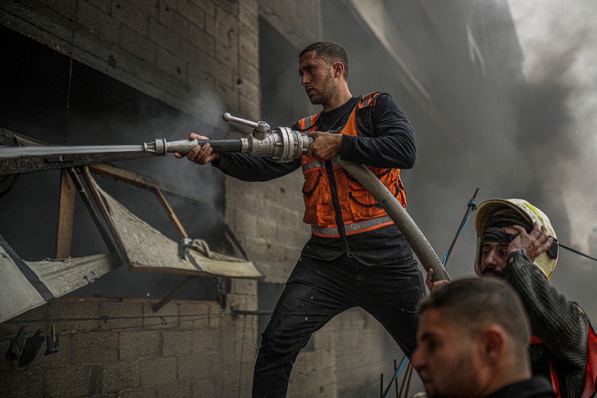 طواقم الدفاع المدني ومتطوعون من المواطنين أثناء محاولة إخماد حريق اندلع في مستودع تابع لمنظمة إغاثة في حي الرمال، غرب مدينة غزة، في 13 فبراير/شباط 2026. صورة: عمر أشتوي