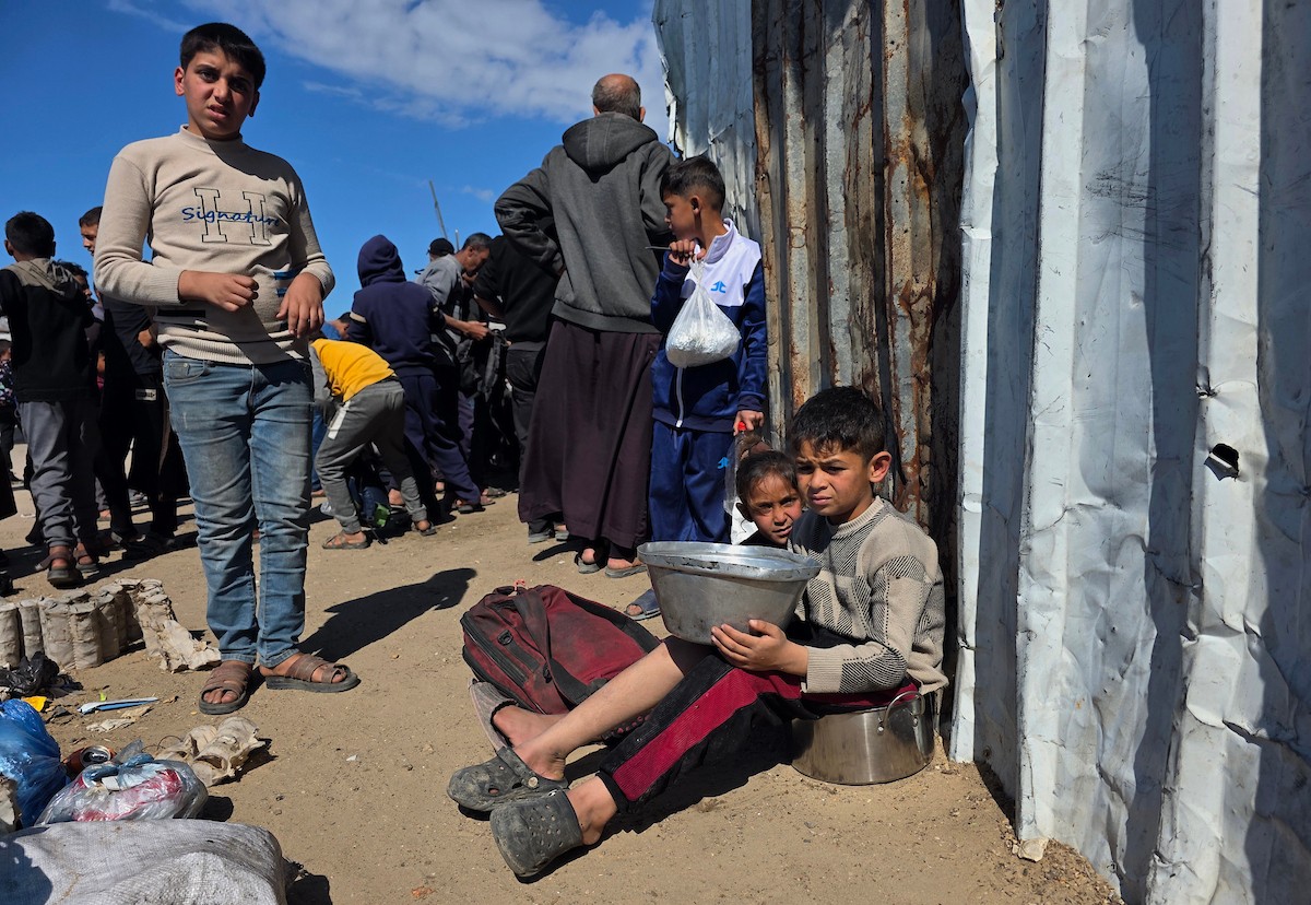 تجمّع فلسطينيون نازحون لتلقّي وجبات طعام من مطبخ خيري في خان يونس، جنوب قطاع غزة، في 24 مارس/آذار 2026. (صورة: طارق محمد)