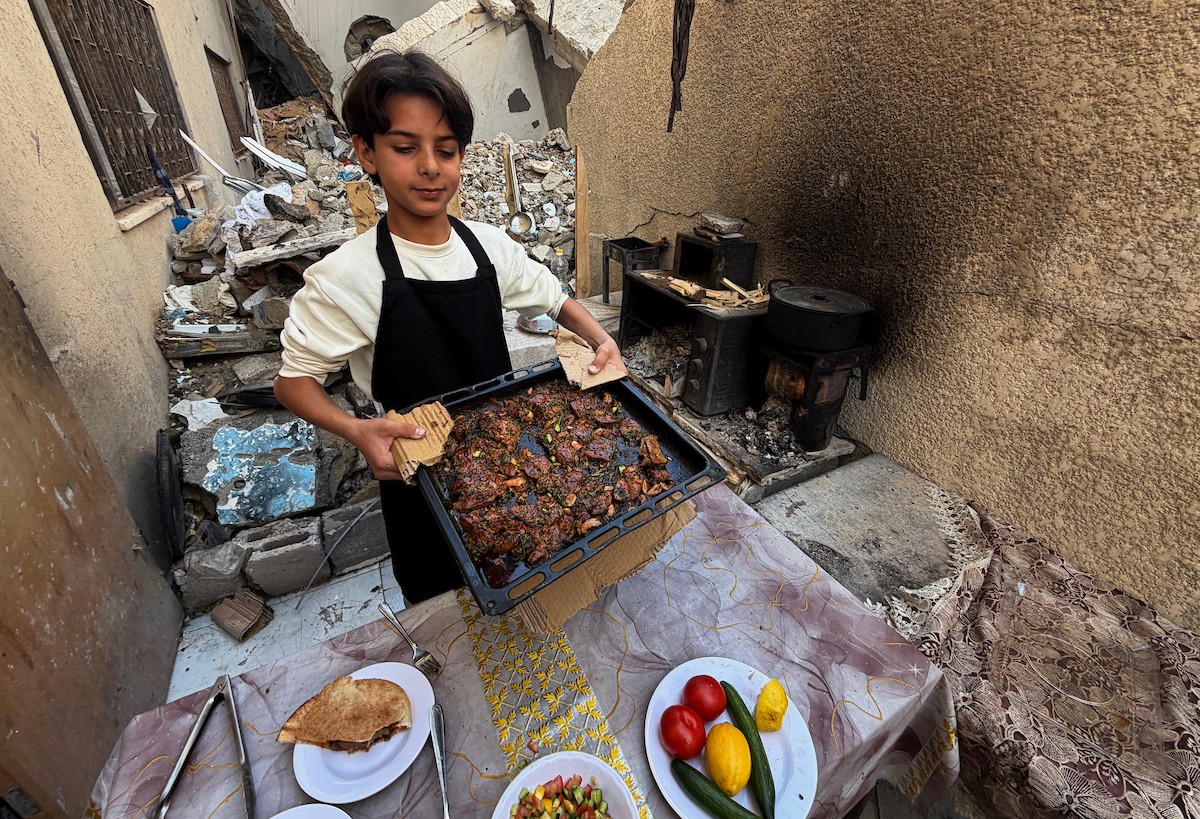 ياسر عياد، فتى فلسطيني يبلغ من العمر أربعة عشر عامًا، يمارس مهاراته في الطبخ على نار الحطب بجوار أنقاض منزل عائلته المدمر في مدينة غزة. غزة، 10 أبريل/نيسان 2026. تصوير: محمد الأسود