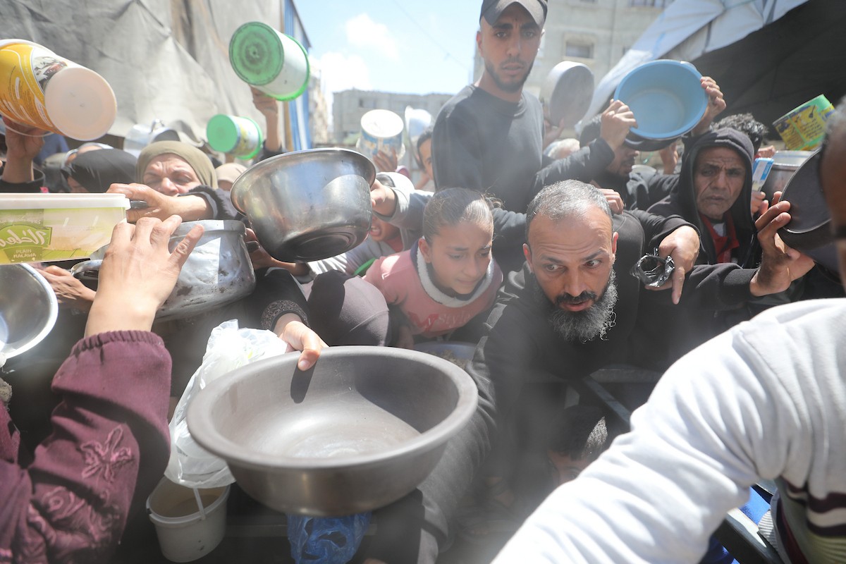 إحدى الجمعيات الخيرية توزع وجبات طعام على الفلسطينيين النازحين في مخيم النصيرات للاجئين، في ظل استمرار نقص الغذاء نتيجةً للسياسة الإسرائيلية المتعلقة بدخول المساعدات إلى مدينة غزة، في 11 أبريل/نيسان 2026. (تصوير: حسن جيدي)