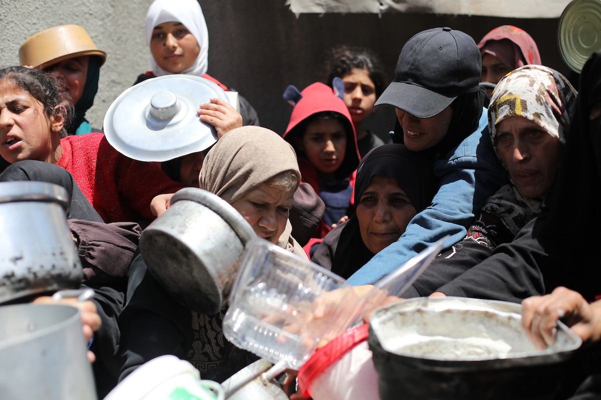 إحدى الجمعيات الخيرية توزع وجبات طعام على الفلسطينيين النازحين في مخيم النصيرات للاجئين، في ظل استمرار نقص الغذاء نتيجةً للسياسة الإسرائيلية المتعلقة بدخول المساعدات إلى مدينة غزة، في 11 أبريل/نيسان 2026. (تصوير: حسن جيدي)