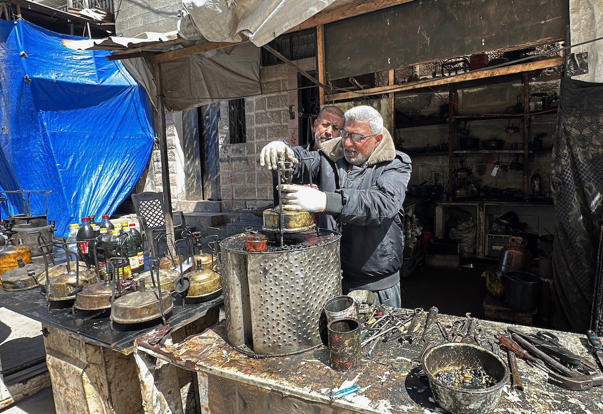عادل عيسى، 63 عامًا، يُصلح مواقد الكيروسين القديمة في ورشته بمخيم الشاطئ، في مدينة غزة، صورة فوتوغرافية لهادي داود