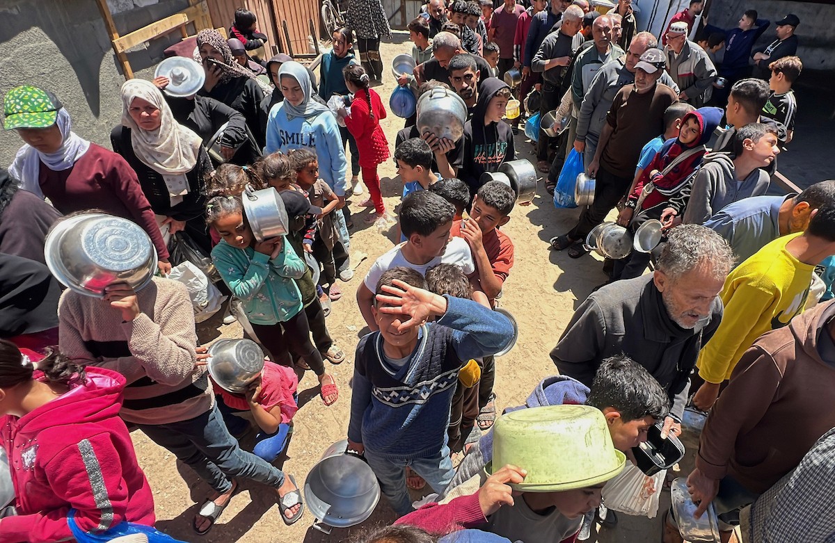 يتلقى فلسطينيون نازحون طعامًا من مطبخ خيري في مخيم النصيرات للاجئين وسط قطاع غزة، في 23 أبريل/نيسان 2026، (صورة: يوسف أبو وطفة)