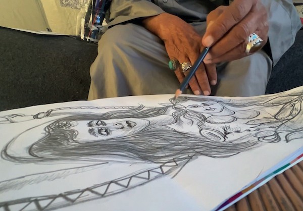 محمد زملط، رجل فلسطيني مسنّ اقتلعته الحرب من مخيم جباليا في شمال قطاع غزة، يحمل اليوم ريشته كوسيلة للبقاء، لا للفن فقط. في خيمته المتواضعة بمخيم البريج وسط القطاع، 12 أبريل/نيسان 2026، عدسة: يوسف أبو وطفة