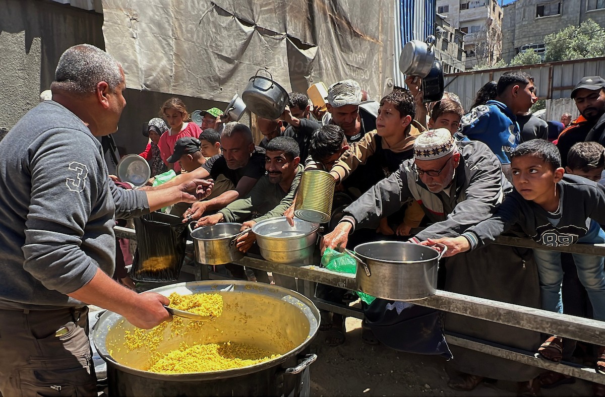 يتلقى فلسطينيون نازحون طعامًا من مطبخ خيري في مخيم النصيرات للاجئين وسط قطاع غزة، في 23 أبريل/نيسان 2026، (صورة: يوسف أبو وطفة)