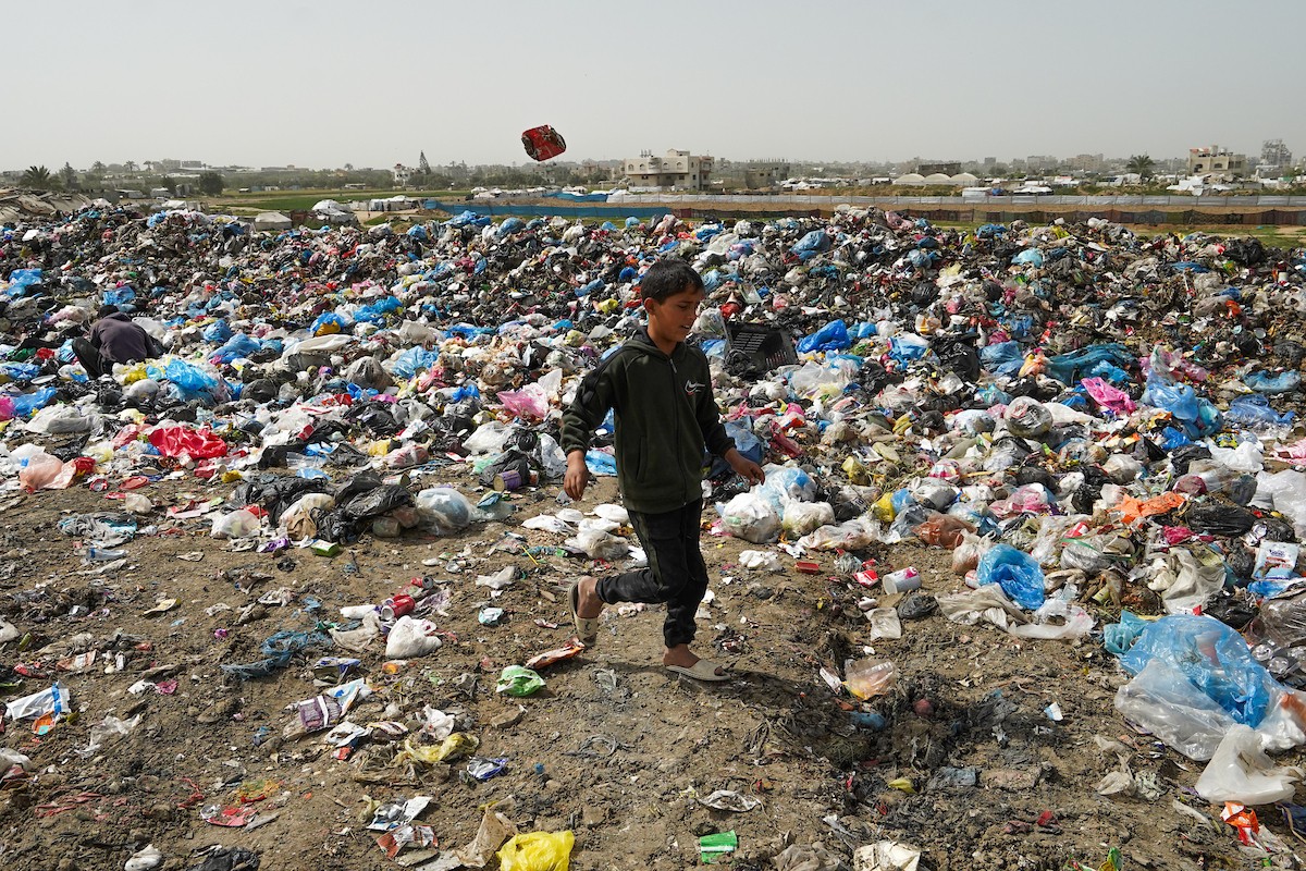 أطفال فلسطينيون يبحثون بين أكوام القمامة عن بقايا الطعام أو الألعاب في مكب نفايات بمخيم البريج للاجئين وسط قطاع غزة، في 4 أبريل/نيسان 2026، بالتزامن مع يوم الطفل الفلسطيني.(صورة: رمزي أبو عامر)