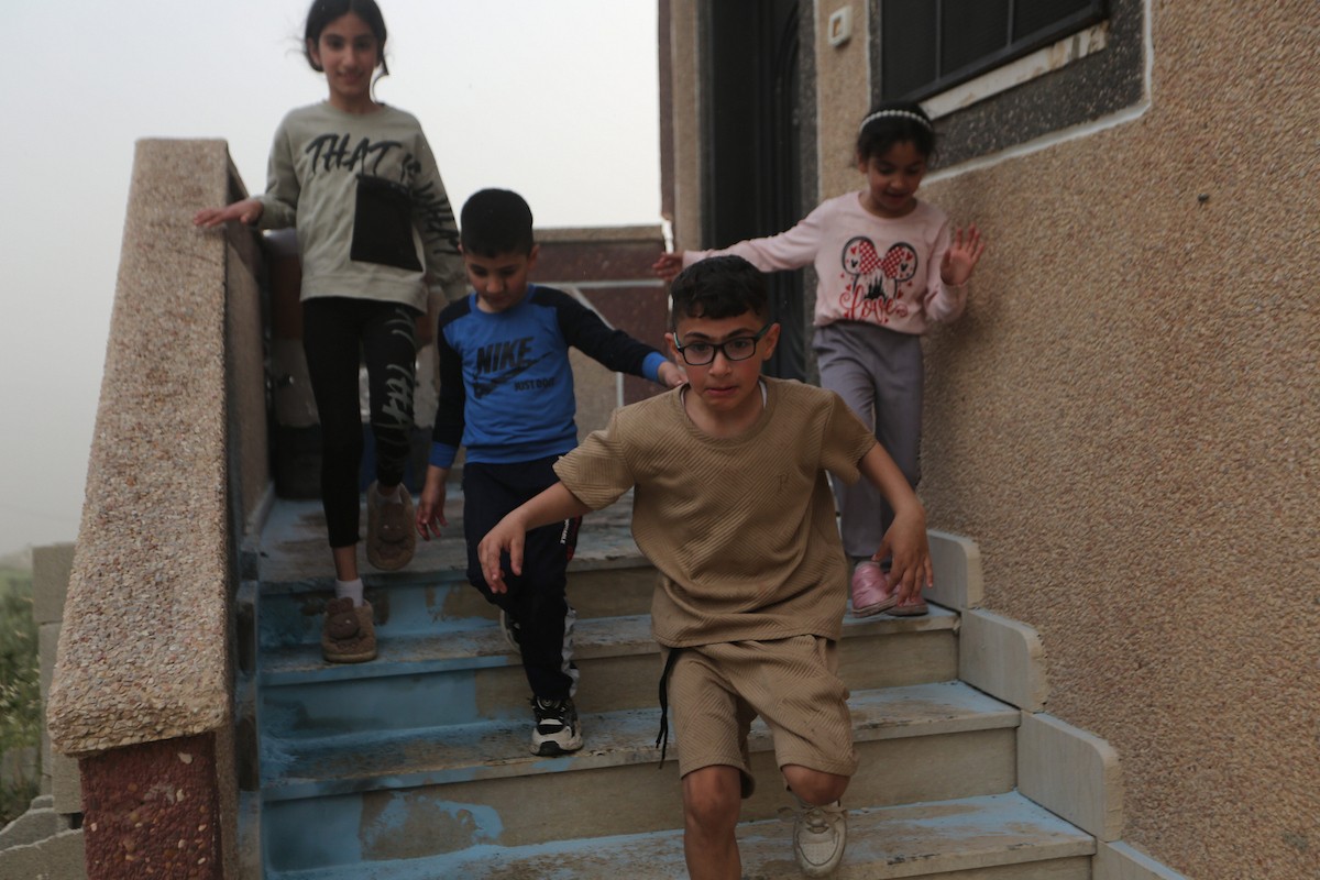 يقف فلسطينيون وسط آثار الدمار في قرية عورتا جنوب نابلس شمال الضفة الغربية، عقب هجوم نفذه مستوطنون إسرائيليون استهدف مركبات ومنازل المواطنين، مخلّفًا أضرارًا واسعة، وفق شهود عيان. 17 أبريل/نيسان 2026. تصوير: محمد ناصر.